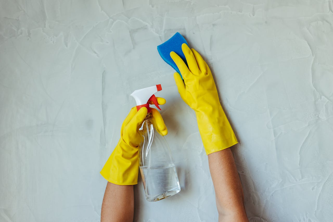 Crafting Captivating Headlines: Your awesome post title goes here Close-up of hands in yellow gloves cleaning a wall with a spray bottle and sponge.