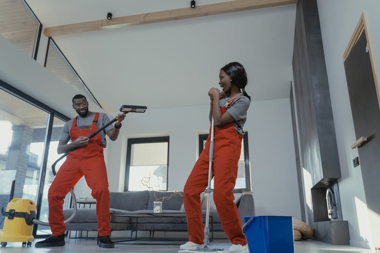 Mastering the First Impression: Your intriguing post title goes here Two adults in vibrant coveralls cleaning a modern home interior, enjoying work.